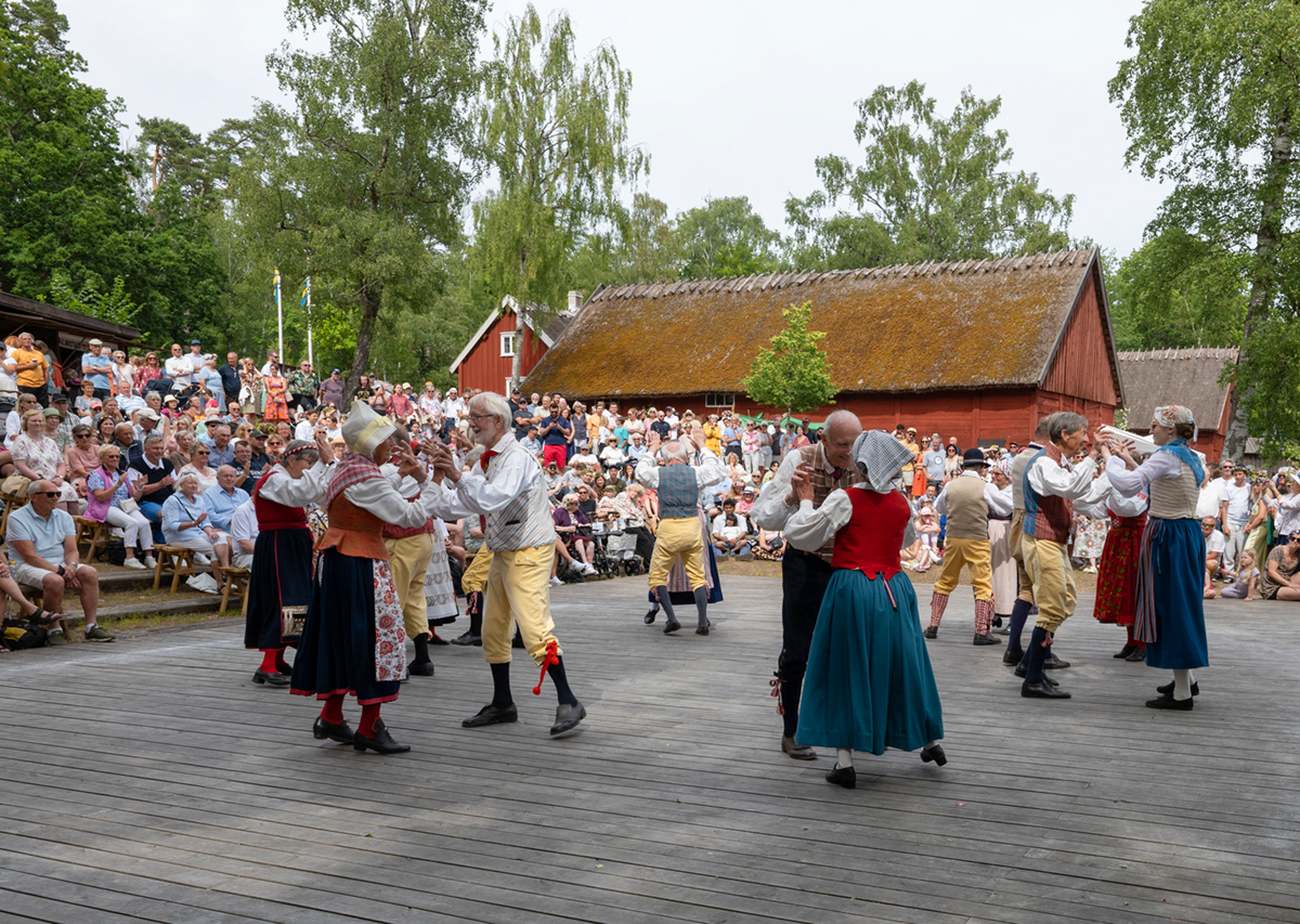 Folkdanslag under en dansuppvisning inför stor publik på Hallandsgården