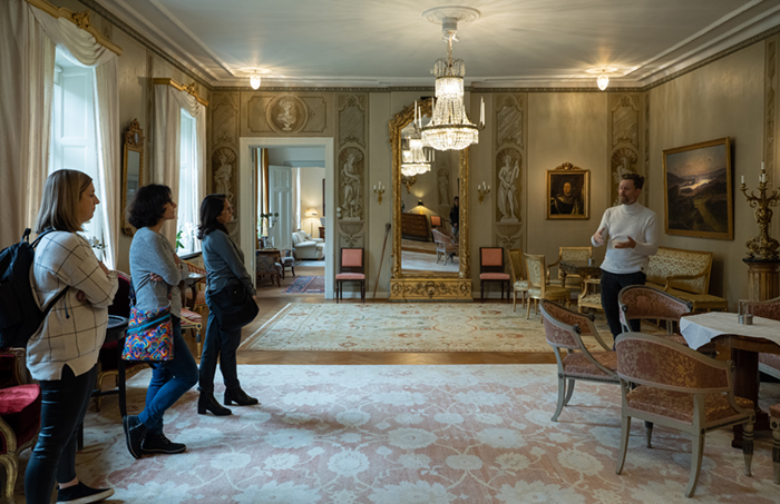 Besökare lyssnar till guide i en sal på Halmstad slott.