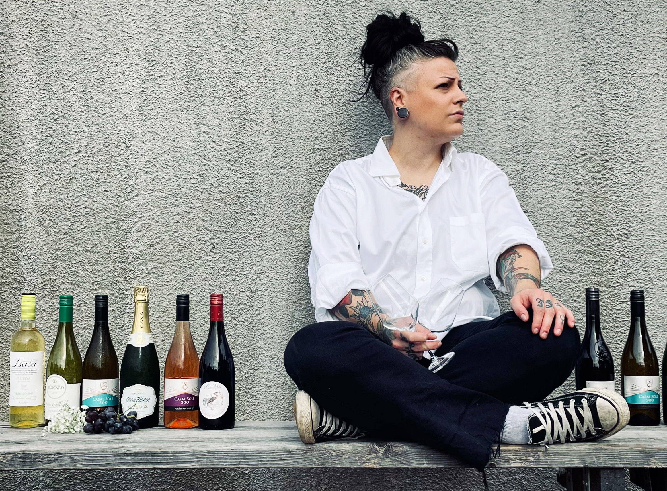 Sommelier sitter på en bänk med vinflaskor uppradade bredvid sig.
