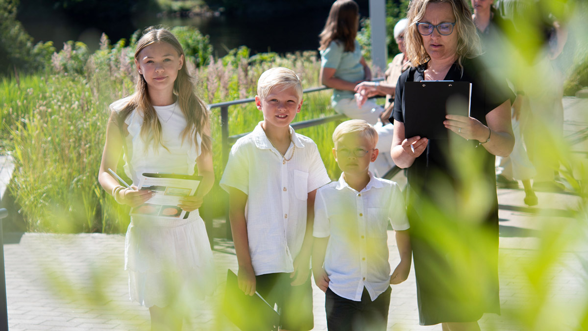 Tre barn och en kvinna i Hallands Konstmuseums trädgård en sommardag.