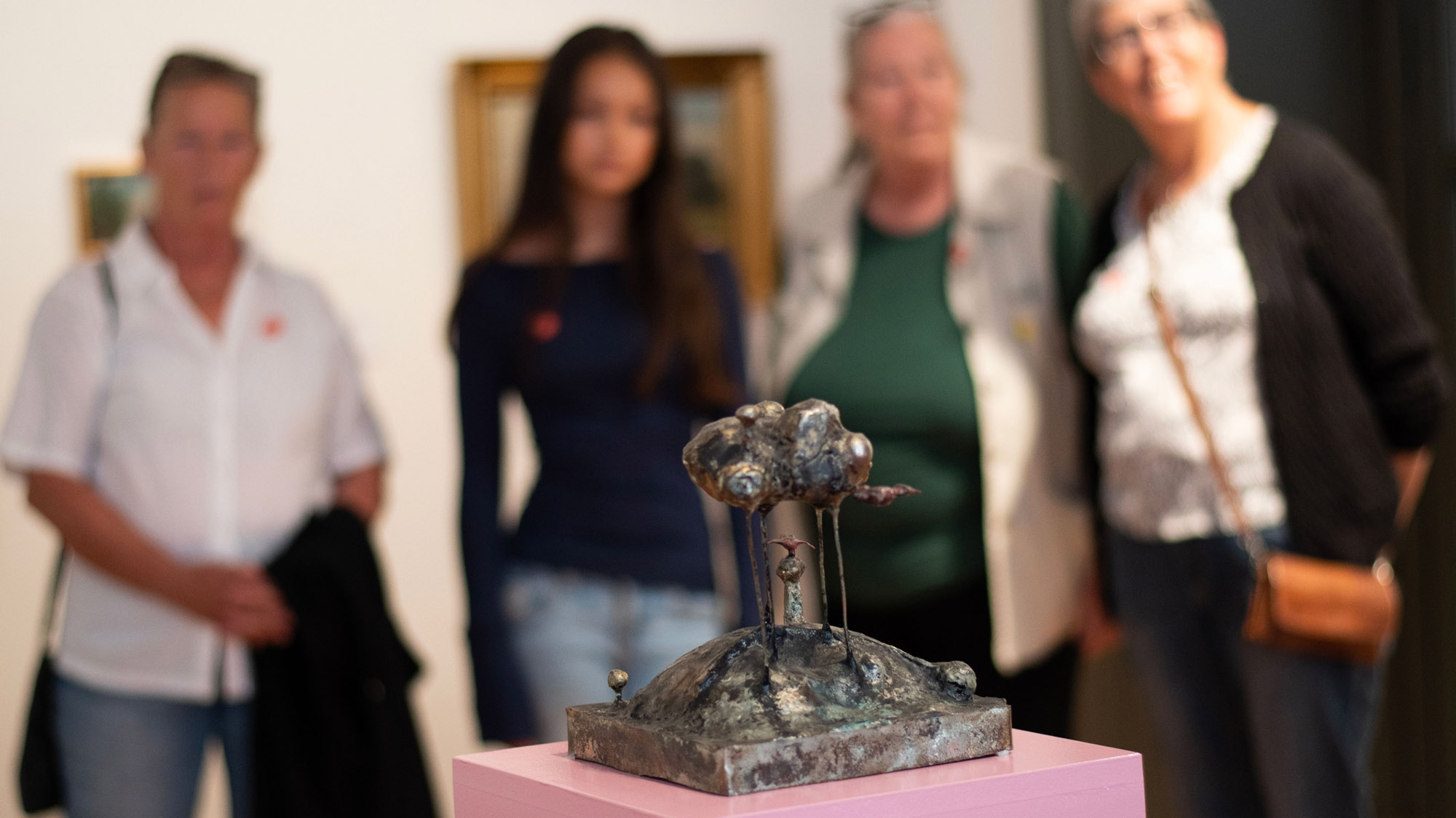 Skulpturen Molnet och Tylajungfrun av Jan Åberg. Besökare på Hallands Konstmuseum står runtomkring och tittar på den.