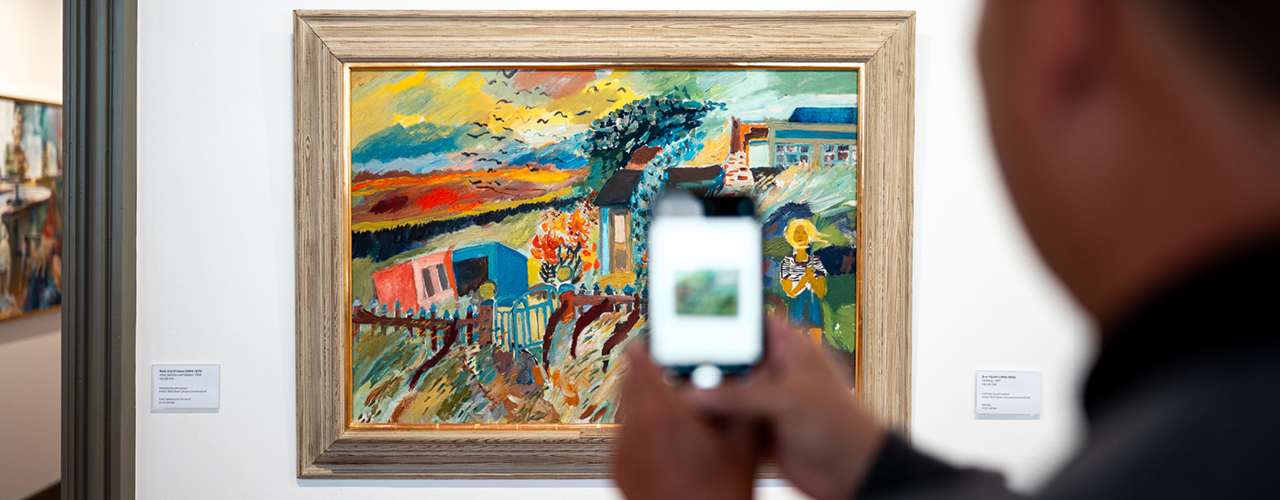 Besökare på Hallands Konstmuseum fotograferar tavla av Sven X:et Erixon med sin mobilkamera.