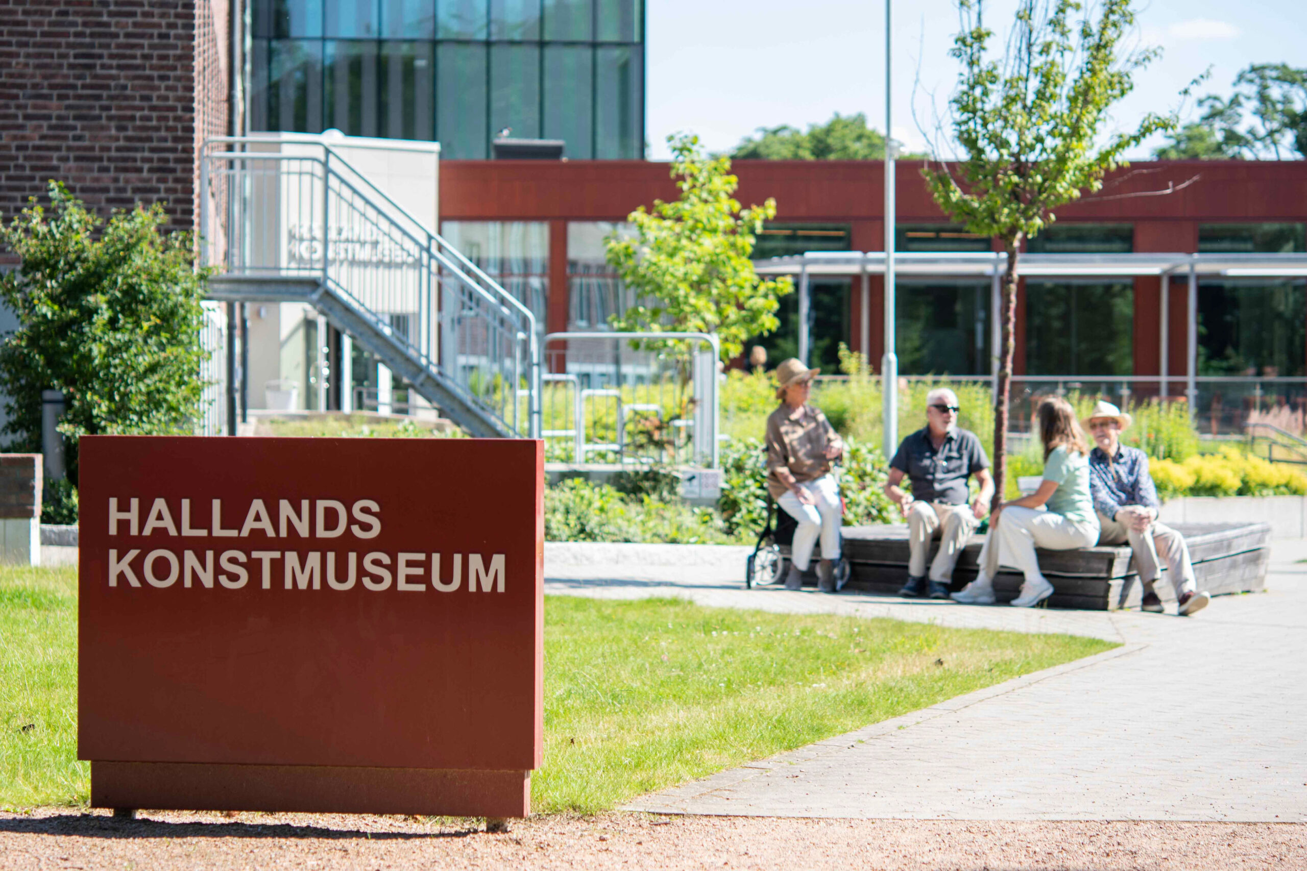 Hallands Konstmuseums trädgård där besökare sitter och njuter av solen.