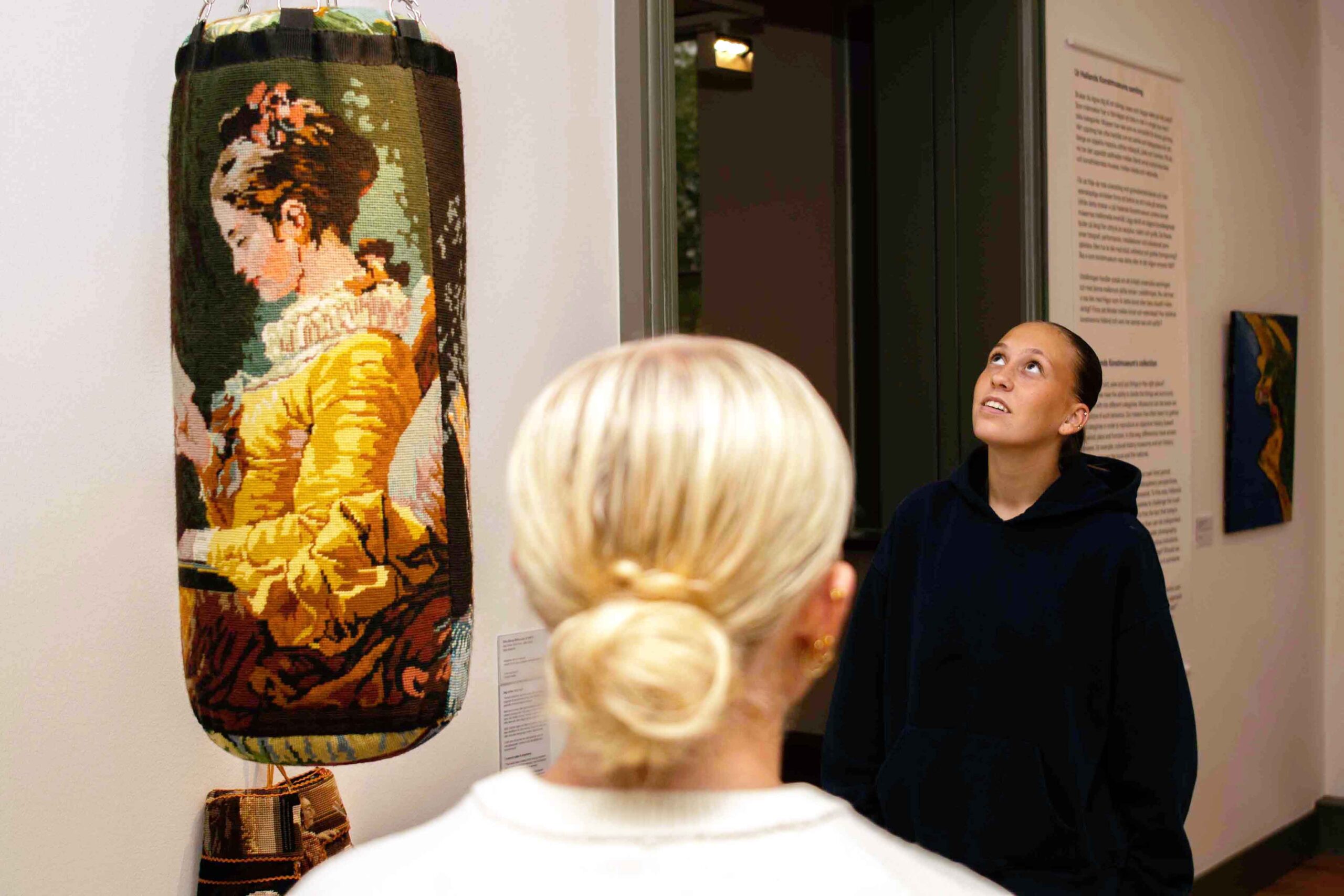 Två besökare framför en boxboll med broderat överdrag.