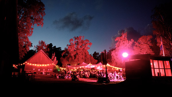 Galgbergsfestivalen på Friluftsmuseet Hallandsgården i nattbelysning. Man ser publiken och ljusgirlanger.