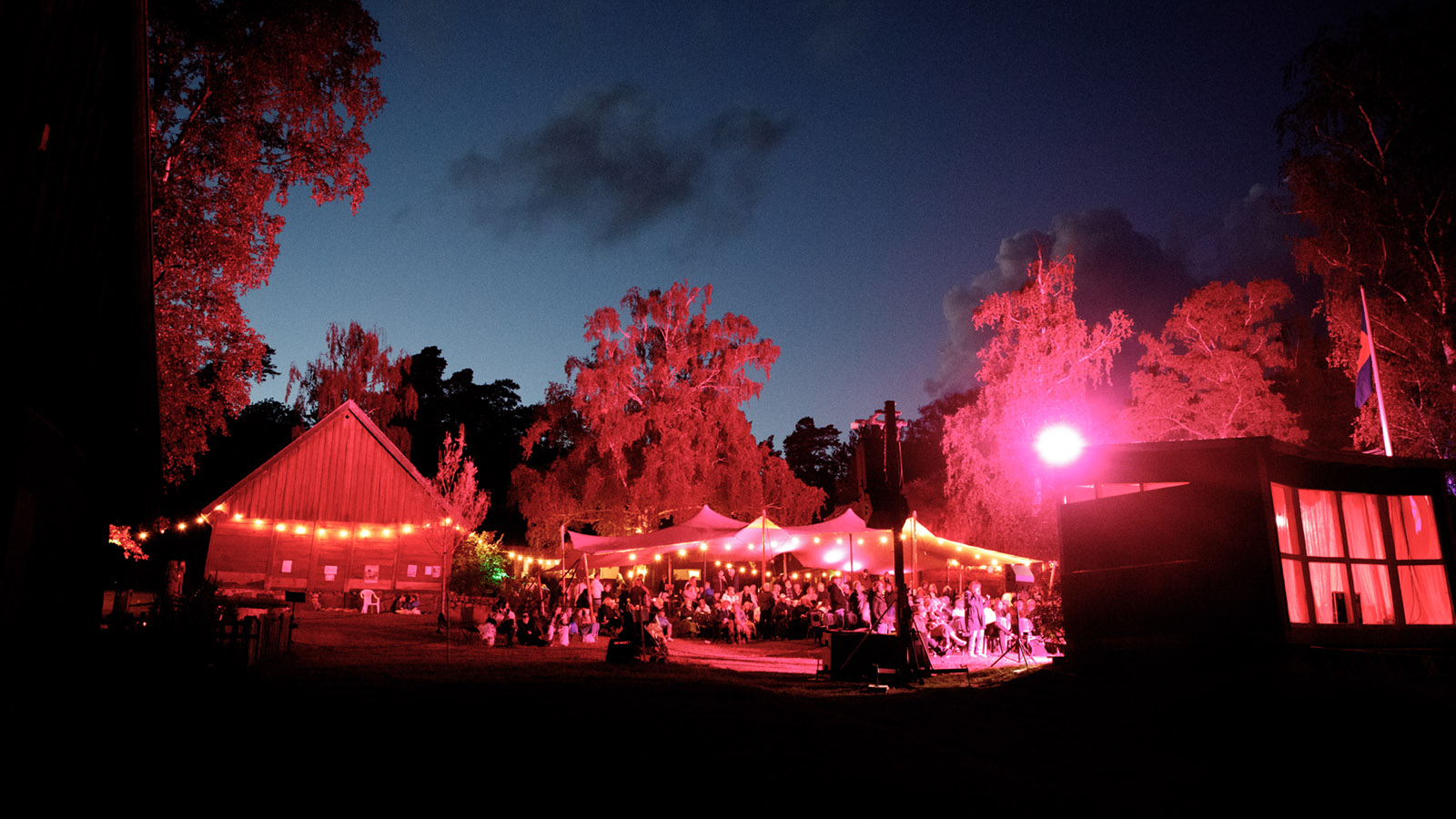 Galgbergsfestivalen på Hallandsgårde i nattbelysning. Man ser publiken och ljusgirlanger.