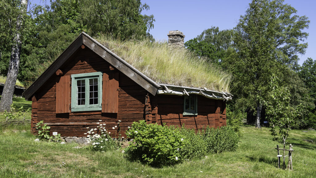 Faluröd, timrad stuga med grästak på Friluftsmuseet Hallandsgården.