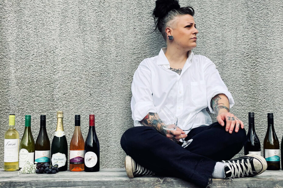 Sommelier sitter på en bänk med vinflaskor brevid sig.