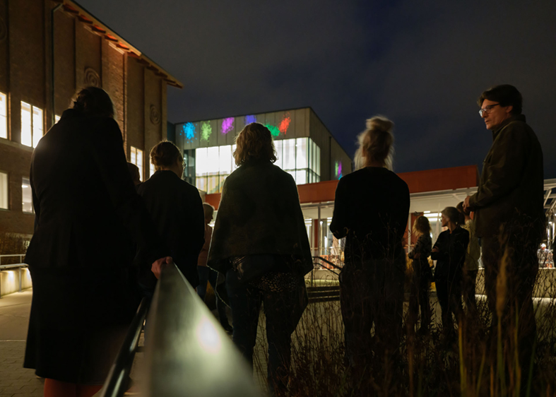 Publik som beskådar ljuskonstverket på Hallands Konstmuseum under en konstpromenad.