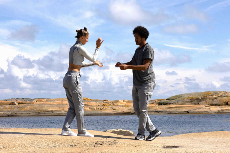 Två dansare på klippor vid vatten.