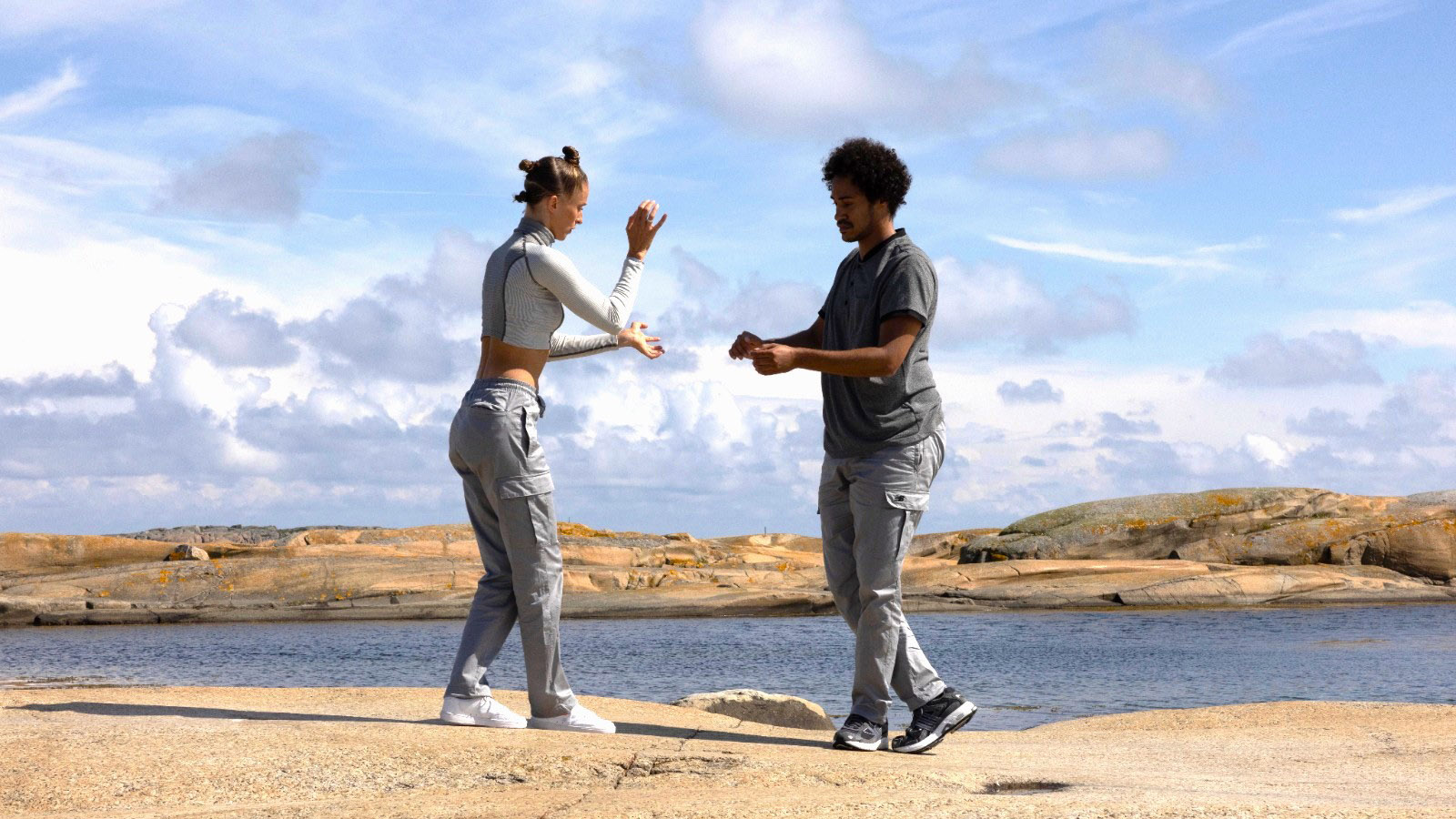 Två dansare på klippor vid vatten.