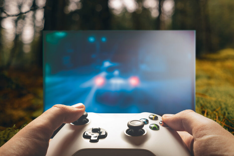 Händer som håller i spelkonsol i en skog.