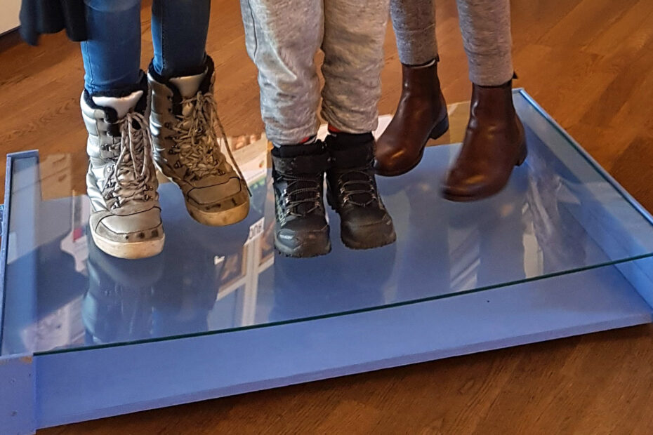 Tre par fötter som står på en glasskiva.
