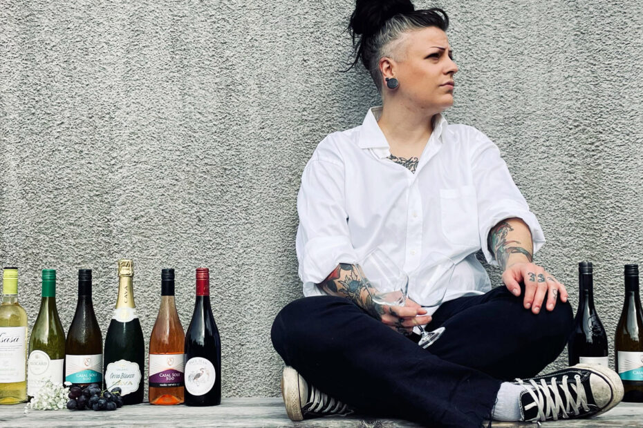 Sommelier sitter i skräddarställning bredvid uppradade vinflaskor.