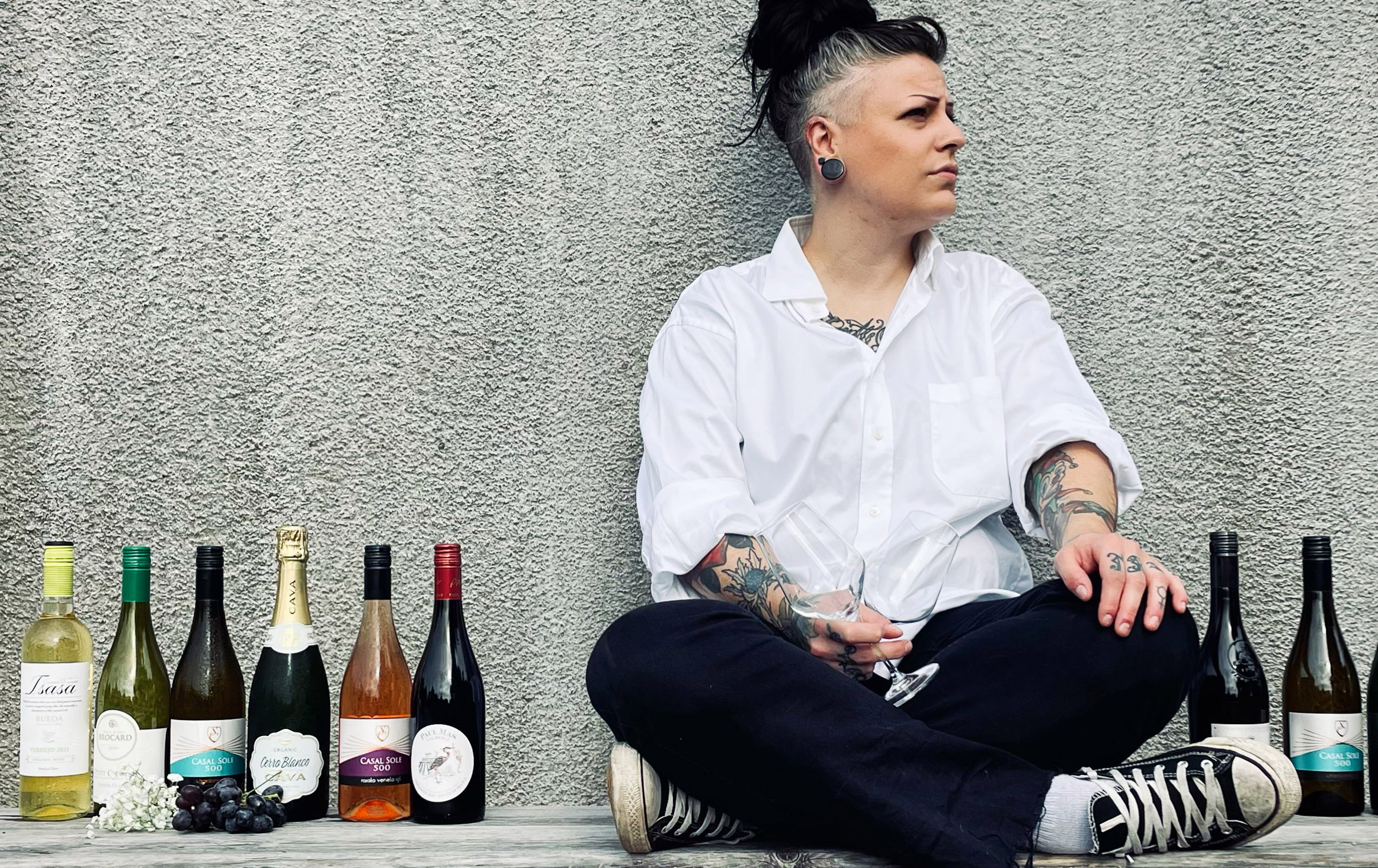 Sommelier sitter i skräddarställning bredvid uppradade vinflaskor.